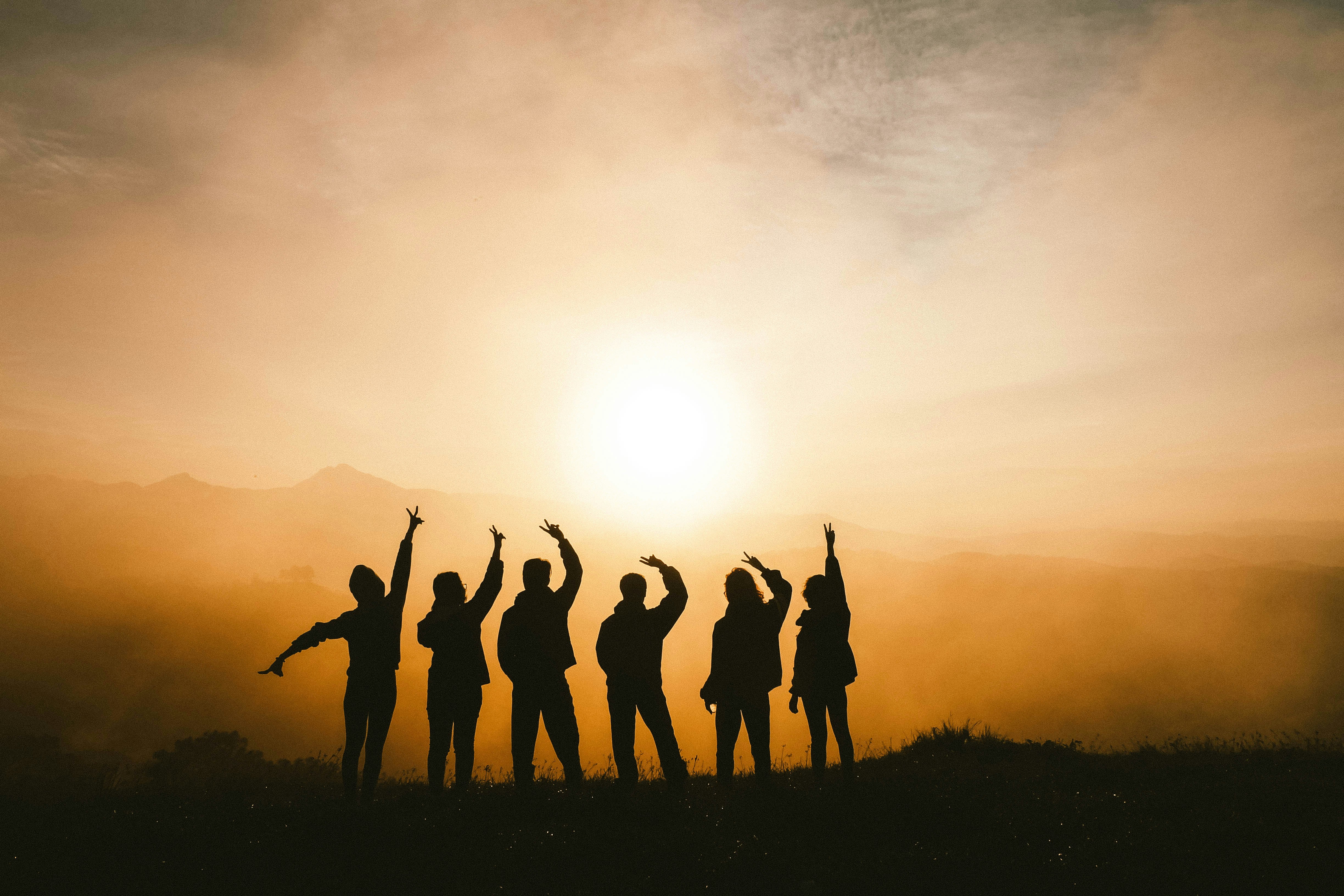 A group of young people's silhouettes in front of a sunset